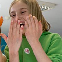 Girl laughing with hands in front of face