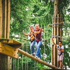 Two adults and child on tree top activity course at Go Ape.