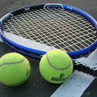 Close up of tennis racquet and two tennis balls.