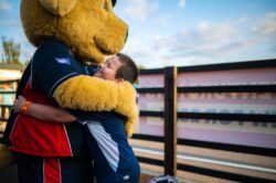 Young boy hugging Bounder the Dog, the Out of Bounds mascot