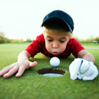Boy blowing golf ball down hole.