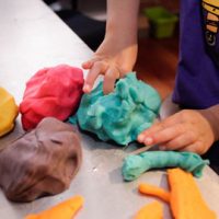 Close up of child's hands playing with playdough.